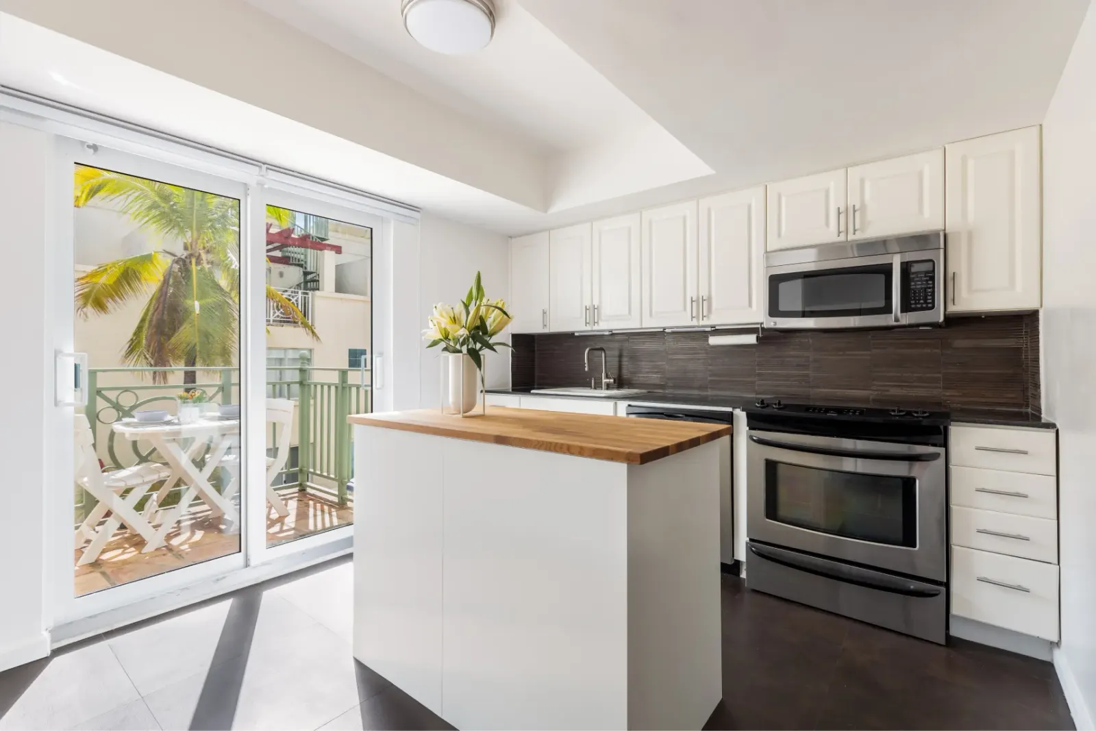 Bright modern kitchen with white cabinets and sliding doors leading to a patio.